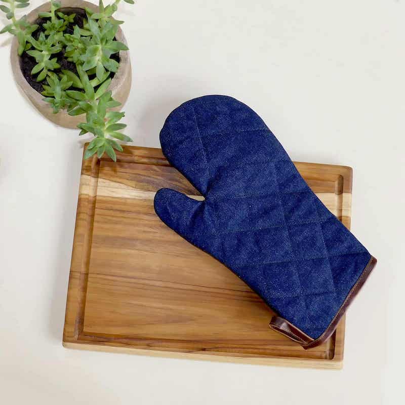 un guante de denim y cuero sobre una tabla de cortar de teca