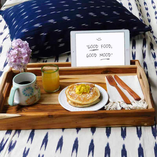 azafate para desayuno con patas plegables puesta sobre una cubre cama blanco con azul