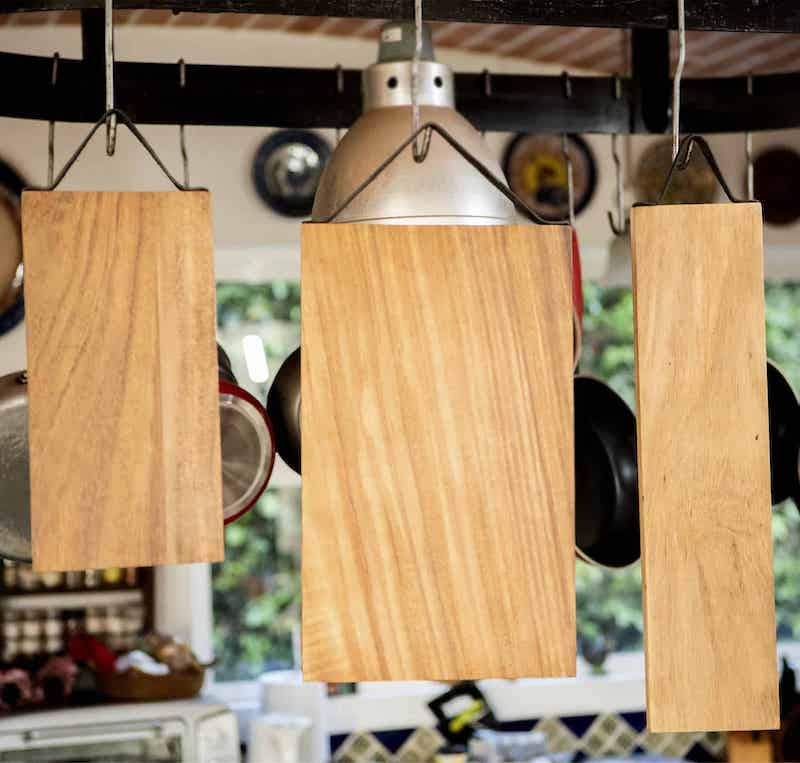 tres tablas de madera con asas de cuero colgadas de ganchos de metal