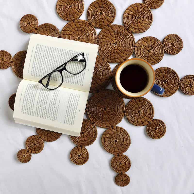 aislador en forma de sol hecho con agujas de pino con un libro y taza de cafe sobre el