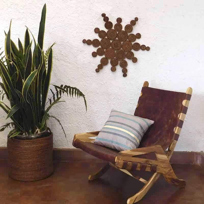sol hecho artesanalmente puesto en una pared junto a una silla de cuero con un cojín en ella