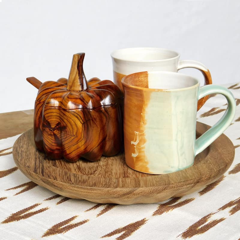 azucarera de madera tallada en forma de calabaza junto a dos tazas de cerámica
