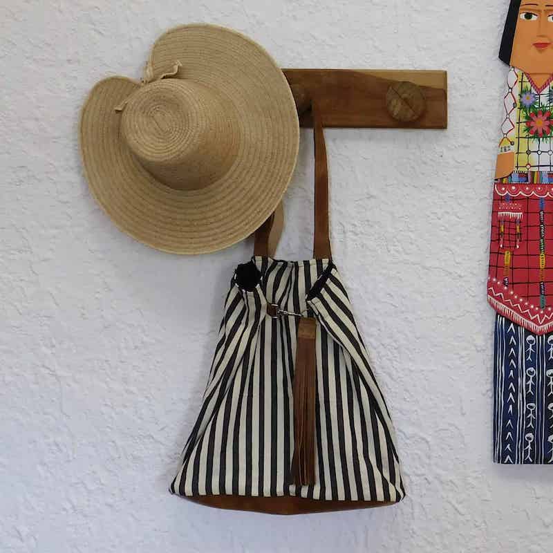 sombrero hecho de hojas de palma colgado junto con una bolsa de tela de algodón y cuero