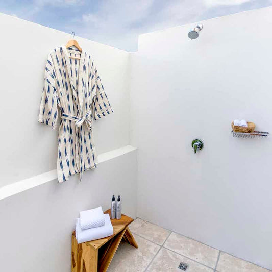 bata blanca con franjas indigo colgada en pared de ducha