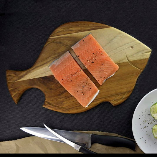 tabla de madera teca para cortar en forma  de pescado con filetes de pescado encima