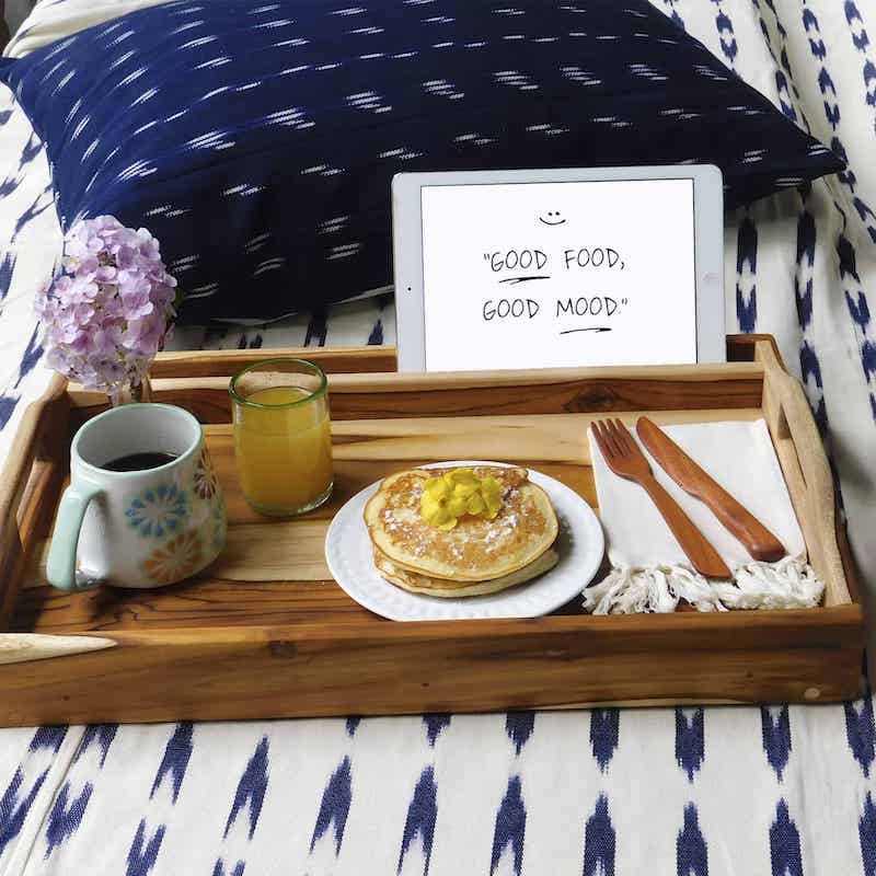 azafate para desayuno con patas plegables puesta sobre una cubre cama blanco con azul