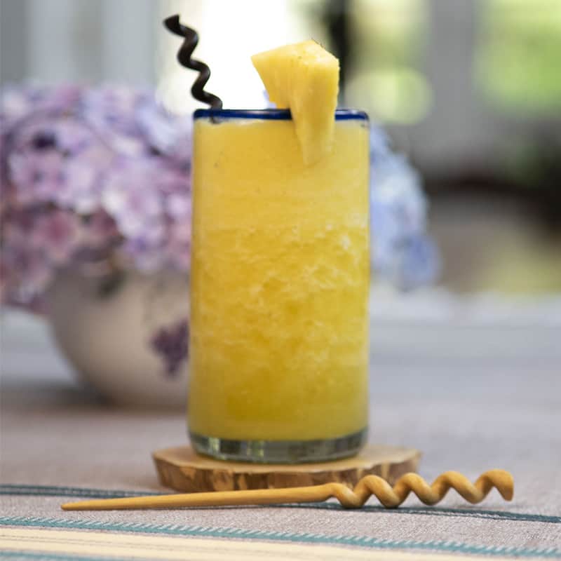 bebida de frutas servida en un baso de vidrio decorado con un agitador de madera en forma de espiral