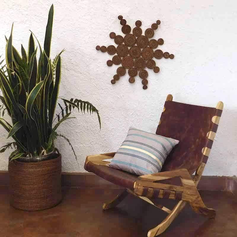 sol hecho artesanalmente puesto en una pared junto a una silla de cuero con un cojín en ella 